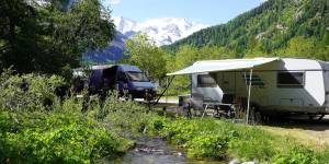 Standplatz für Wohnwagen und Kastenwagen am Bach mit den Berggipfeln im Hintergrund
