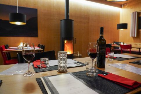 Am Tisch im Restaurant Aratsch mit einem Glas Rotwein aus unserer hervorragenden Auswahl und Cheminée-Feuer