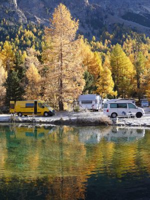 Camper nebst goldigen Lärchen im Sonnenaufgang auf dem Campingplatz Morteratsch im Engadin